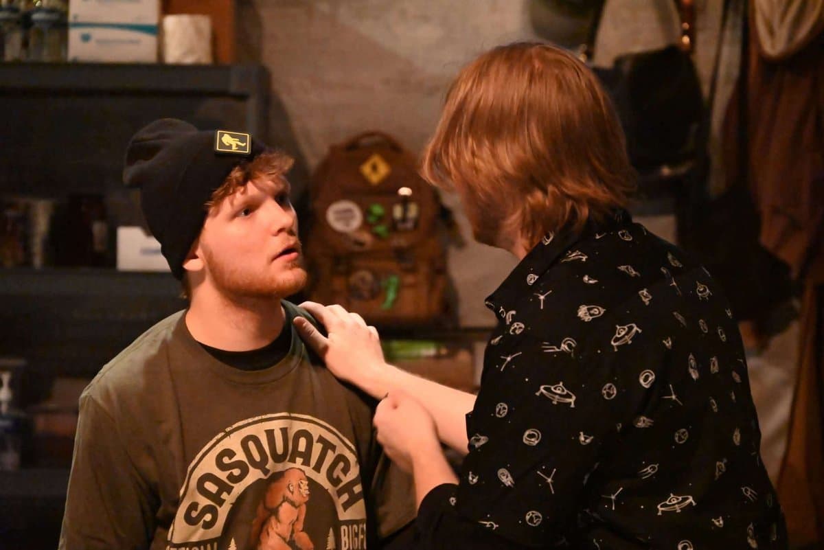 Doug grabs the collar of another male actor who stares up at him wide-eyed in a tense confrontation