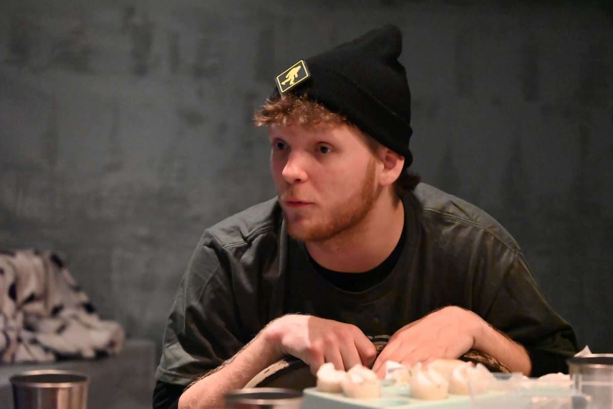 Close-up of a male actor leaning on the table with an intense, focused expression