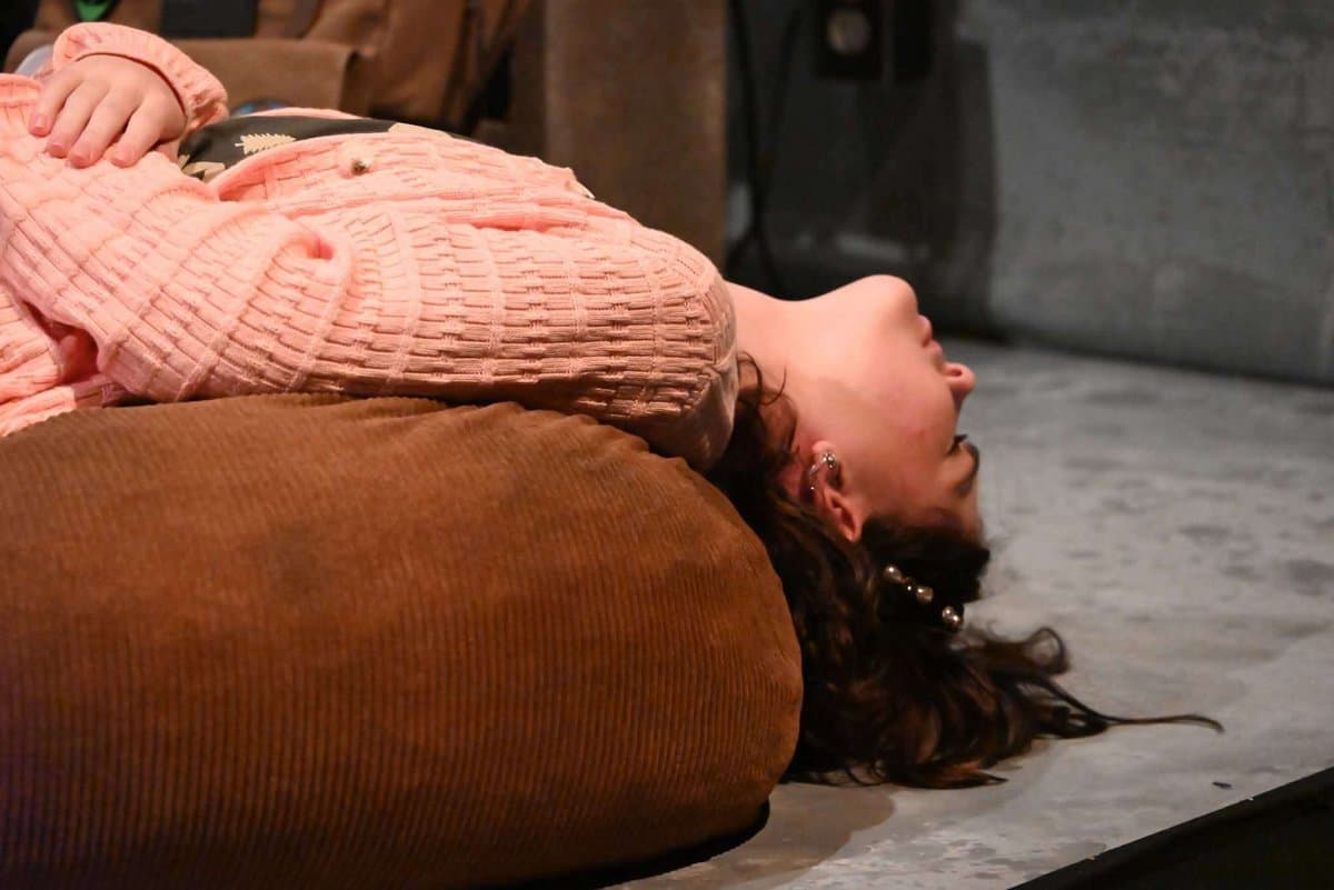Female actor lying dramatically on the stage floor, head tilted back